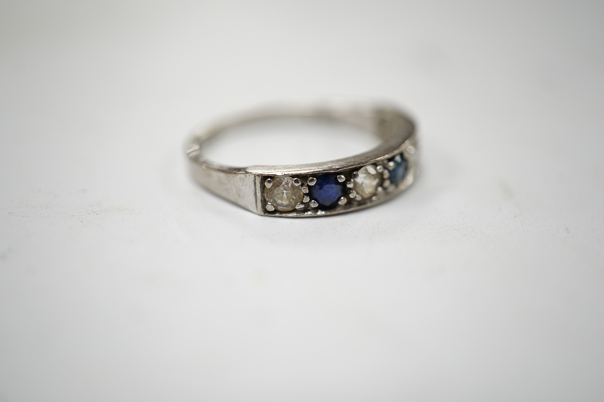 A 1970's 18ct white gold, sapphire and simulated diamond set half hoop ring, size O, gross weight 3.5 grams. Condition - fair